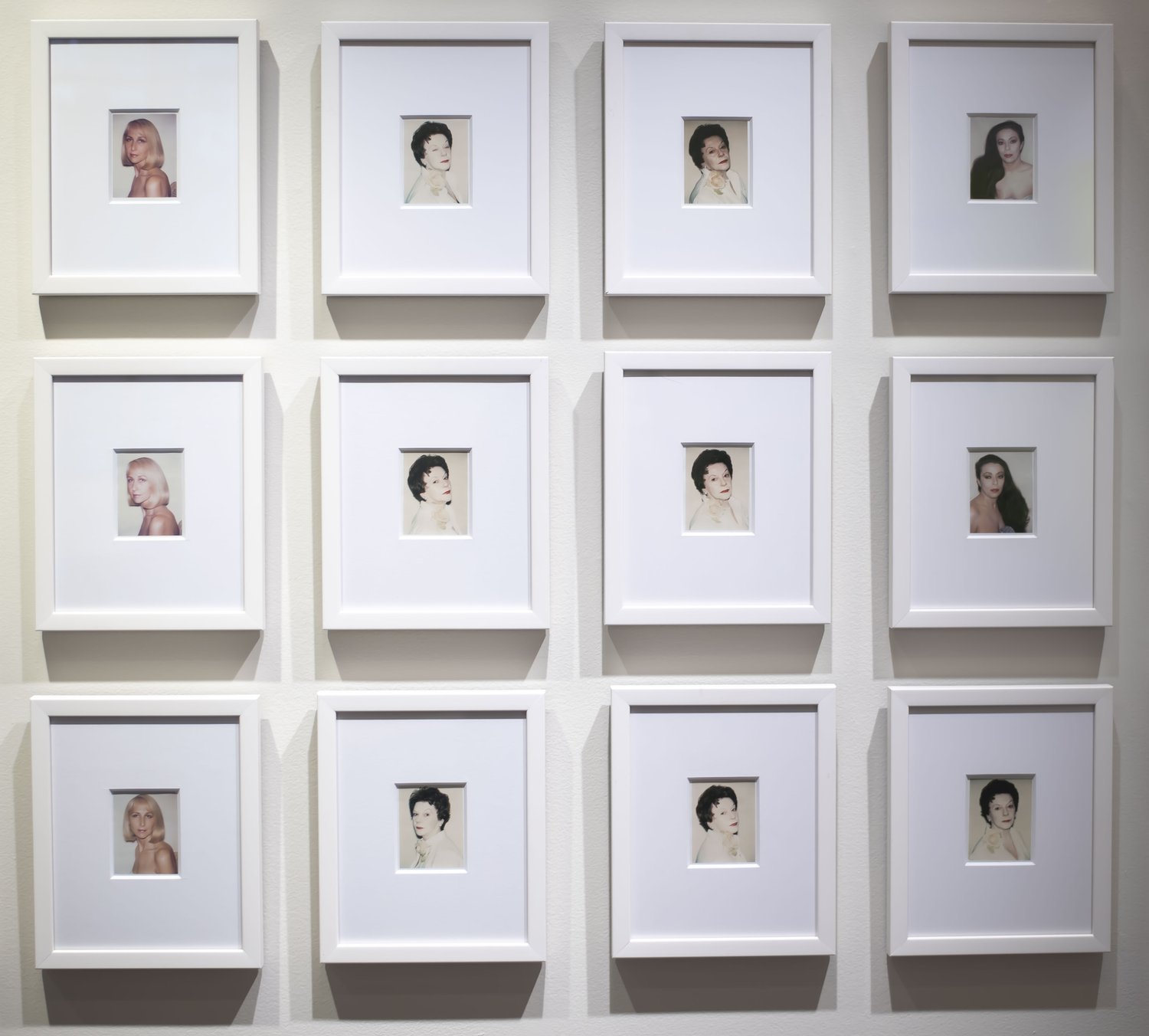 Gallery view of Warhol's portraits hanging in a grid.