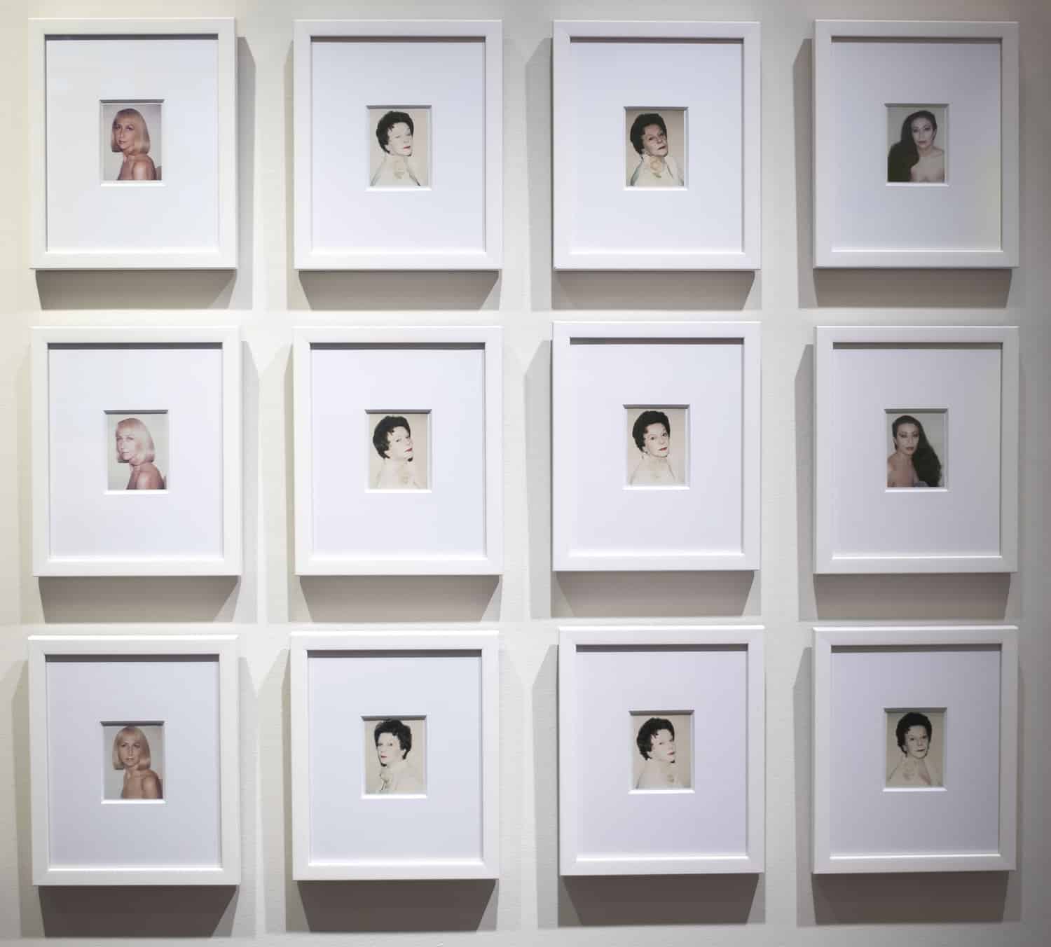 Gallery view of Warhol's portraits hanging in a grid.