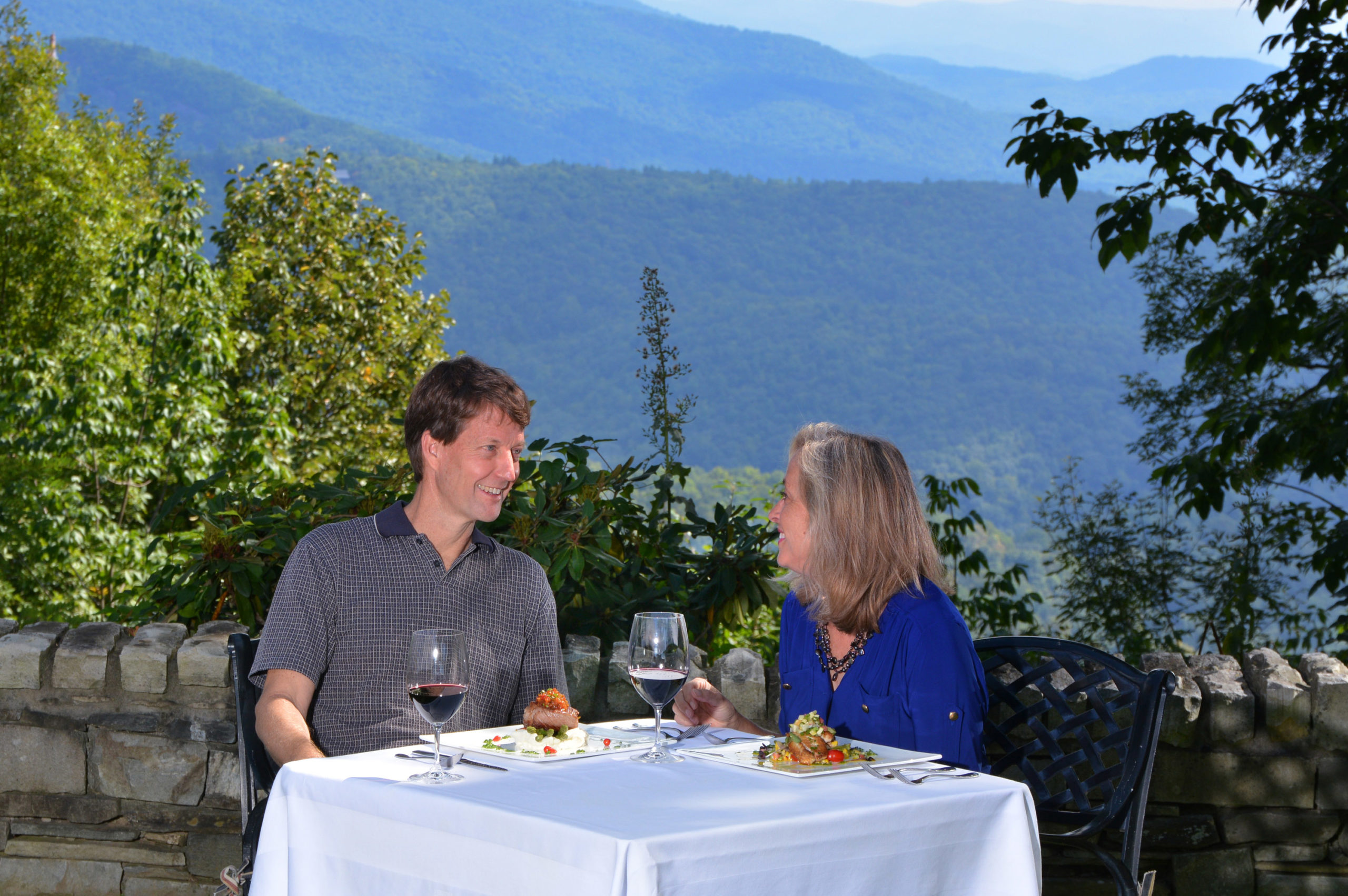 Couple dines outdoors in a mountain setting.