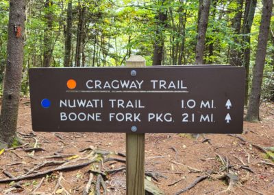 A sign reads Cragway Trail at the top. Nuwati Trail 1 mi and Boone Fork Pkg 2.1 mi are listed underneath