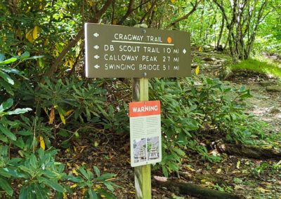 A trail sign reads Cragway Trail, DB Scout Trail 1.0 mi, Calloway Peak 2.7 mi, Swinging Bridge 5.1 mi.