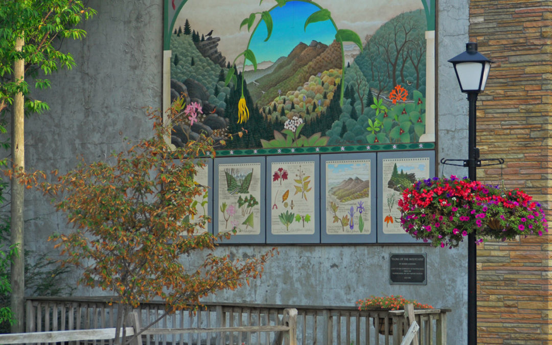 Mural depicting local plants on a wall in town, surrounded by flowers.